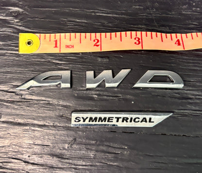 AWD emblem with a ruler for scale on a wooden surface