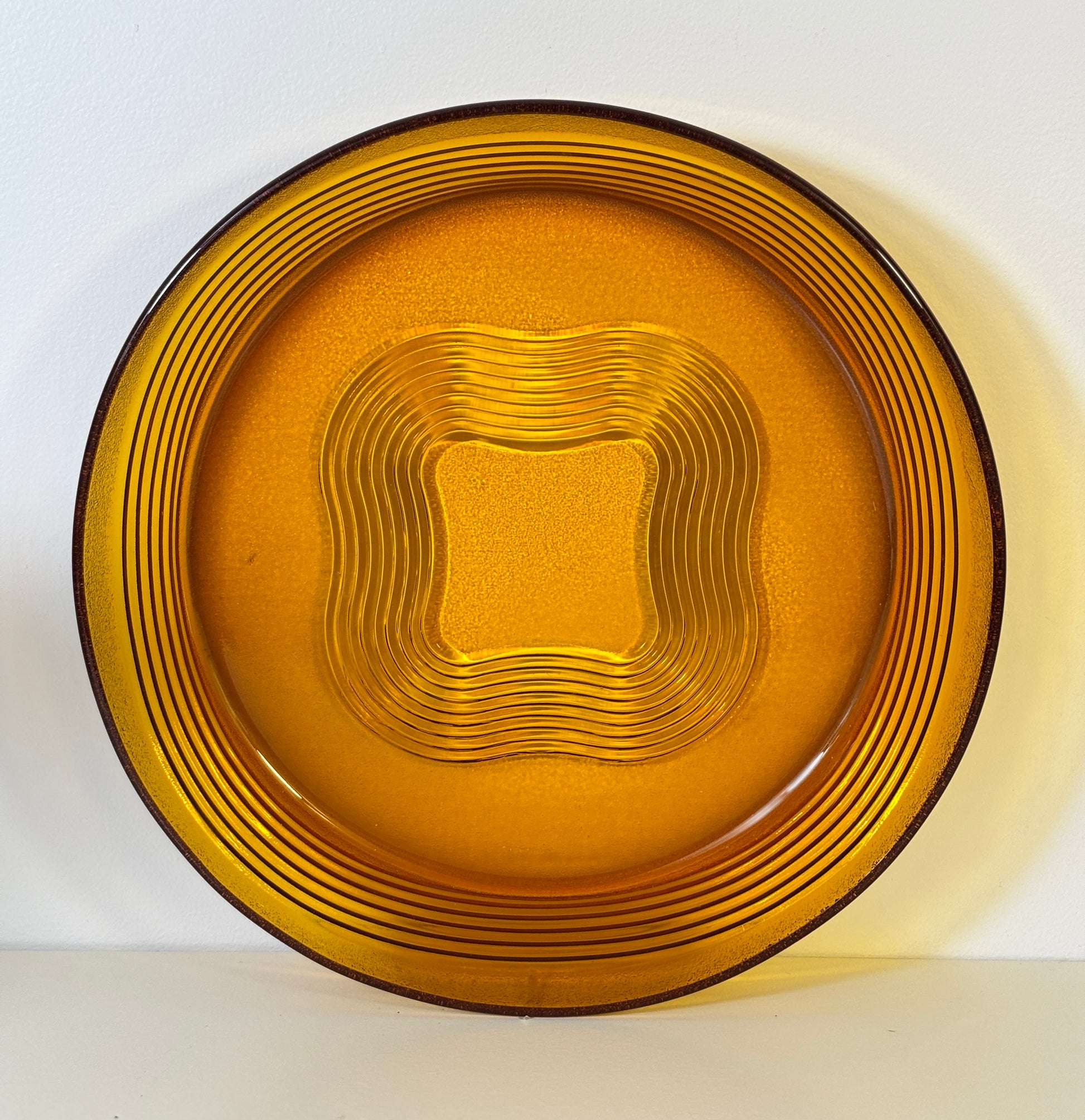 Gold-colored glass plate with concentric circle pattern on a white background