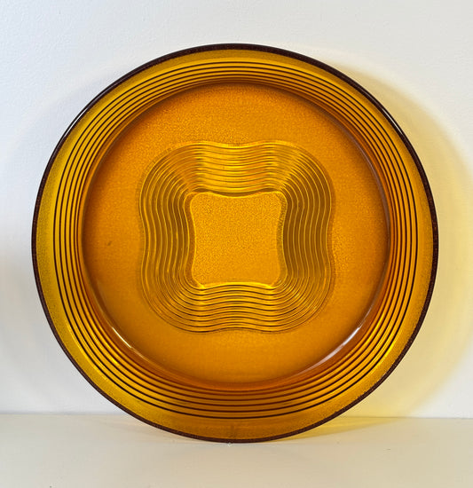 Gold-colored glass plate with concentric circle pattern on a white background