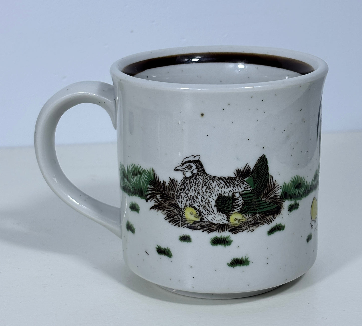 Ceramic mug with a chicken and chicks design on a white background