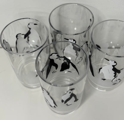 Four glass tumblers with penguin designs on a white background