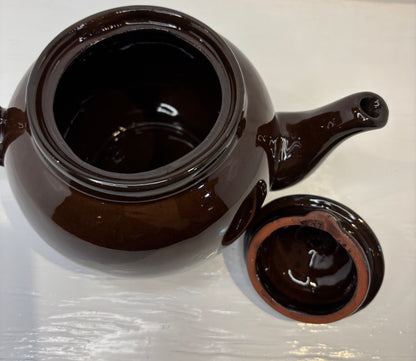 Brown ceramic teapot with lid on a white surface