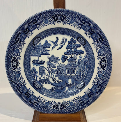 Blue and white decorative plate with intricate patterns on a stand against a neutral background