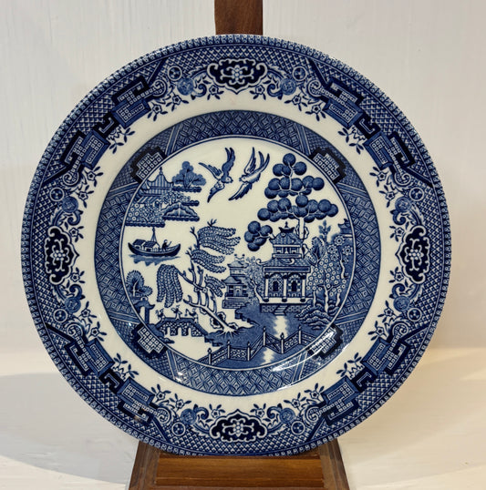 Blue and white decorative plate with intricate patterns on a stand against a neutral background