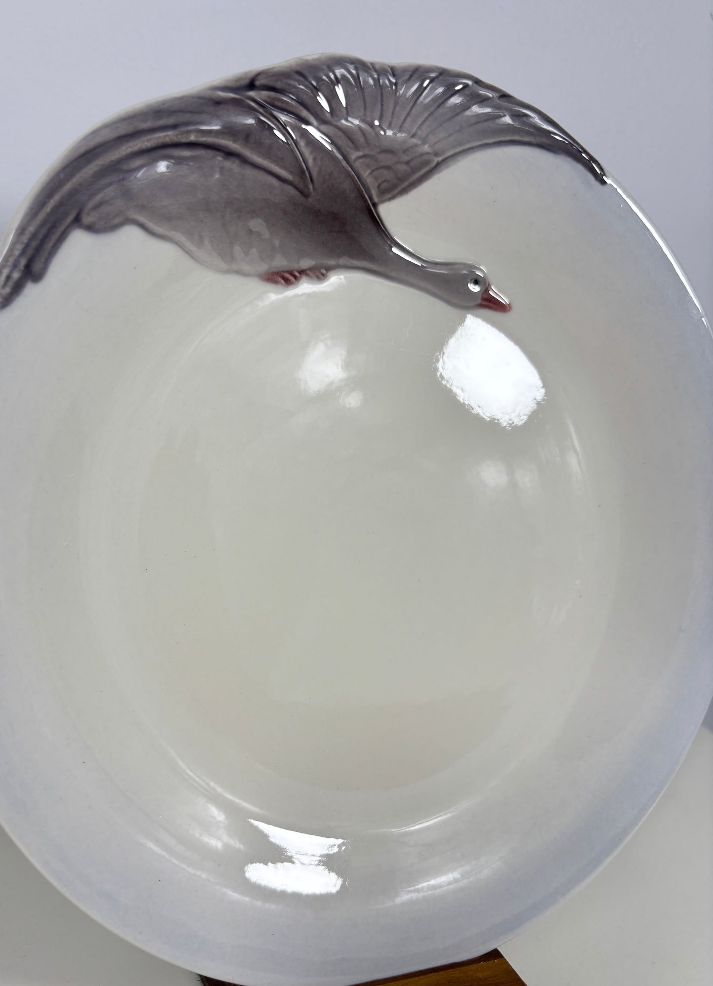 A white ceramic bowl featuring a raised gray goose design along the rim, shown against a plain light background.