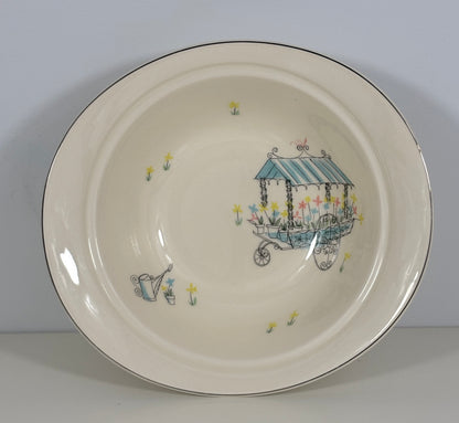 Ceramic plate with a decorative design of a cart and flowers on a plain background