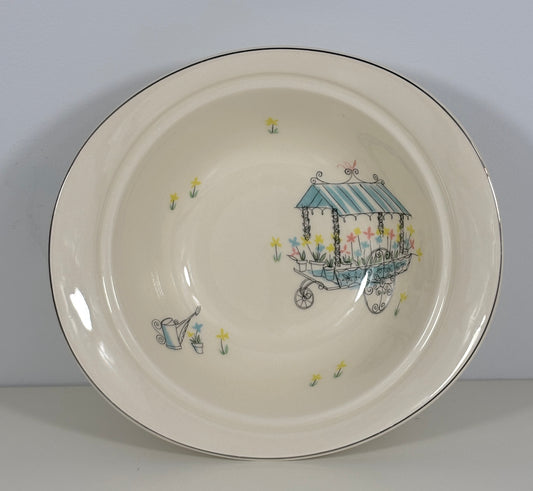 Ceramic plate with a decorative design of a cart and flowers on a plain background