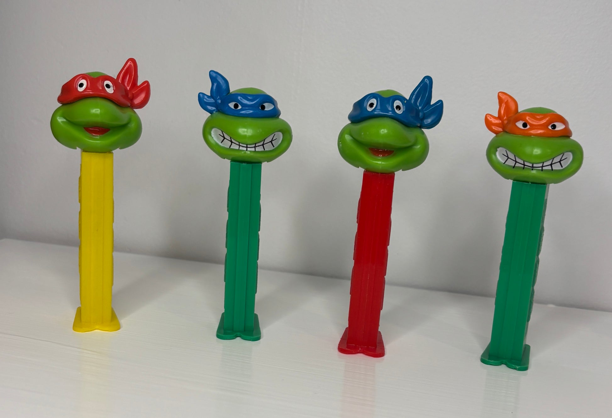 Four colorful PEZ dispensers with character heads on a white background