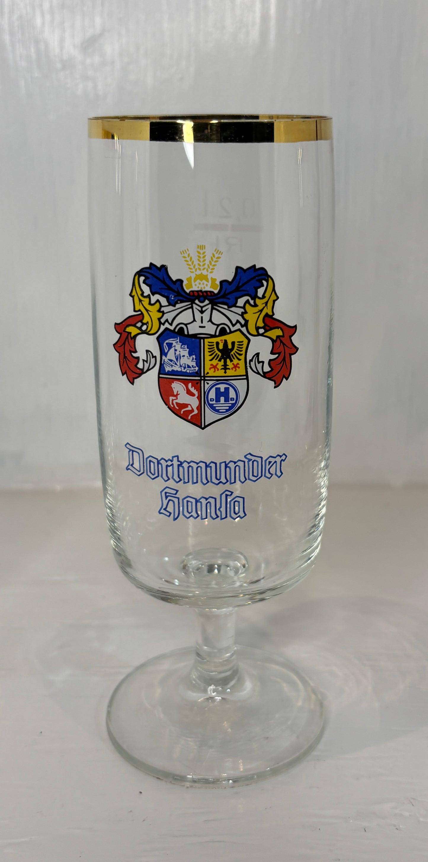 Glass with gold rim and coat of arms on a white background