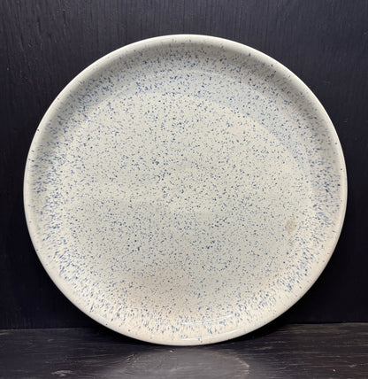 Speckled ceramic plate on a dark background
