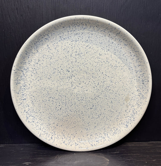 Speckled ceramic plate on a dark background