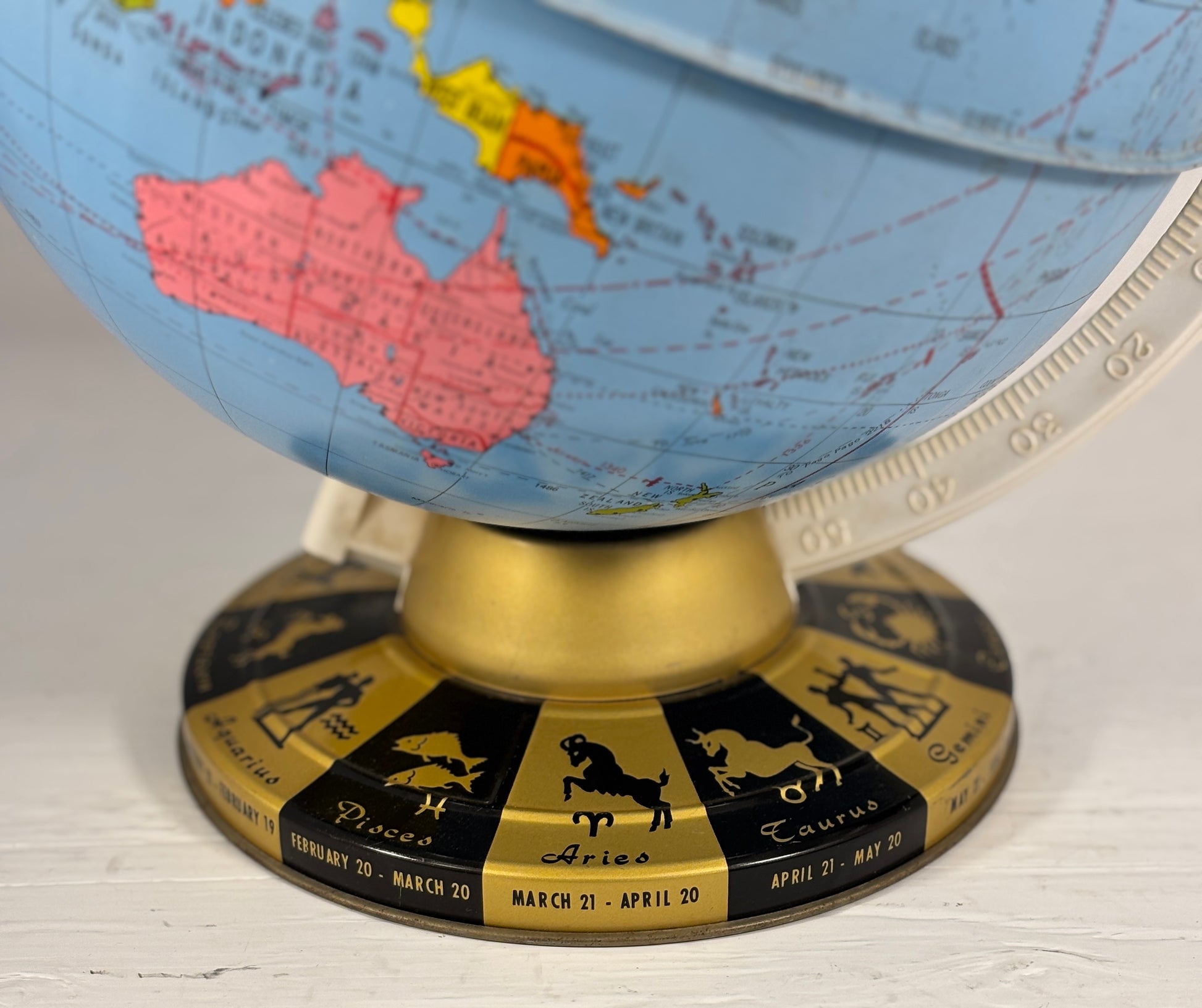 Globe with zodiac signs on the base, on a light wooden surface
