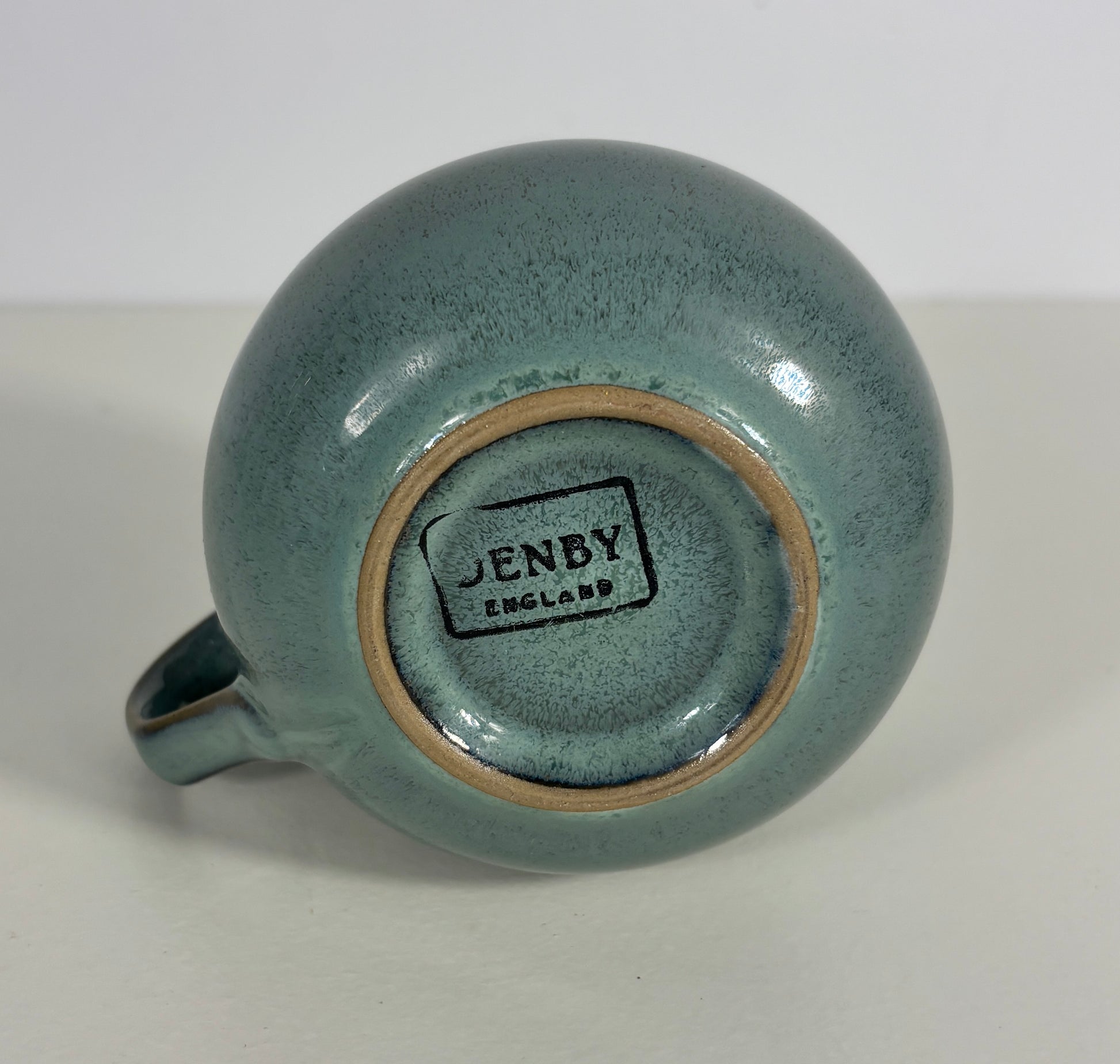 Teal ceramic mug with 'Jenby England' branding on a white background