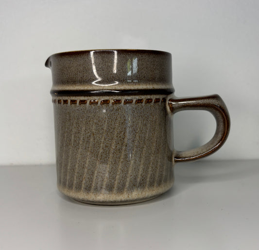 Brown ceramic pitcher with handle on a white background