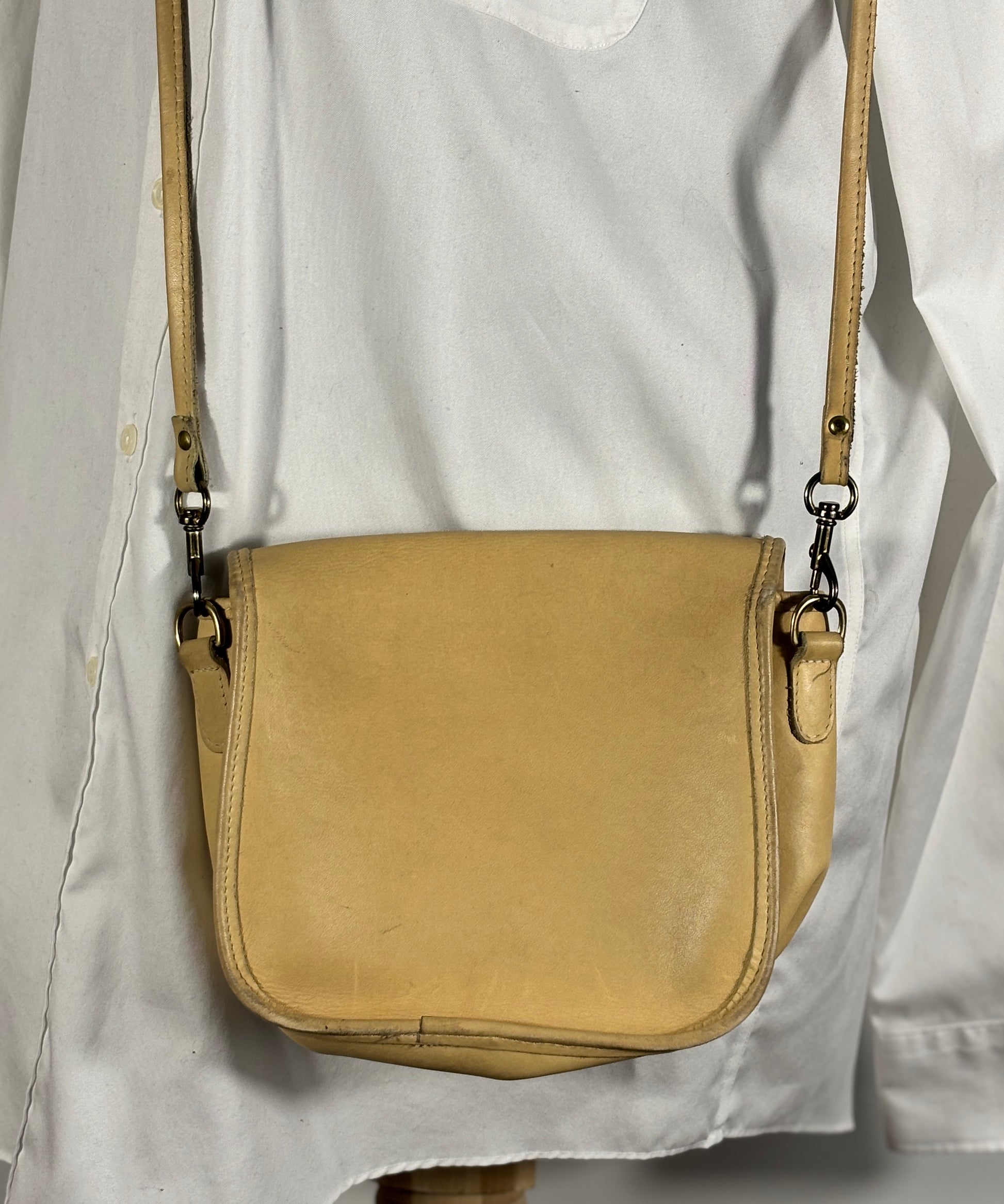 Beige leather crossbody bag on a white shirt
