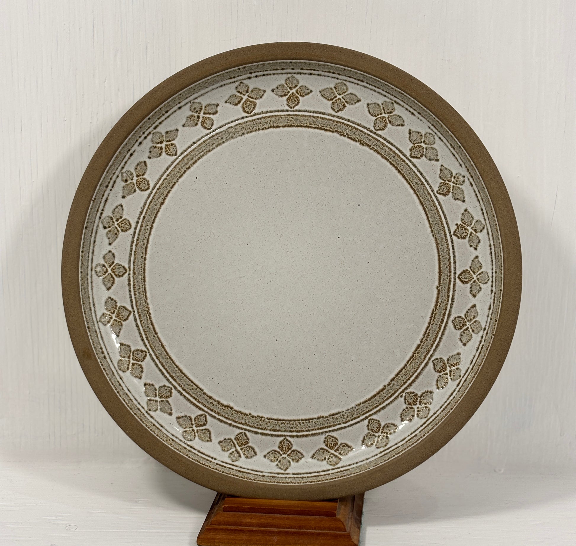Decorative plate with floral patterns on a stand against a white background