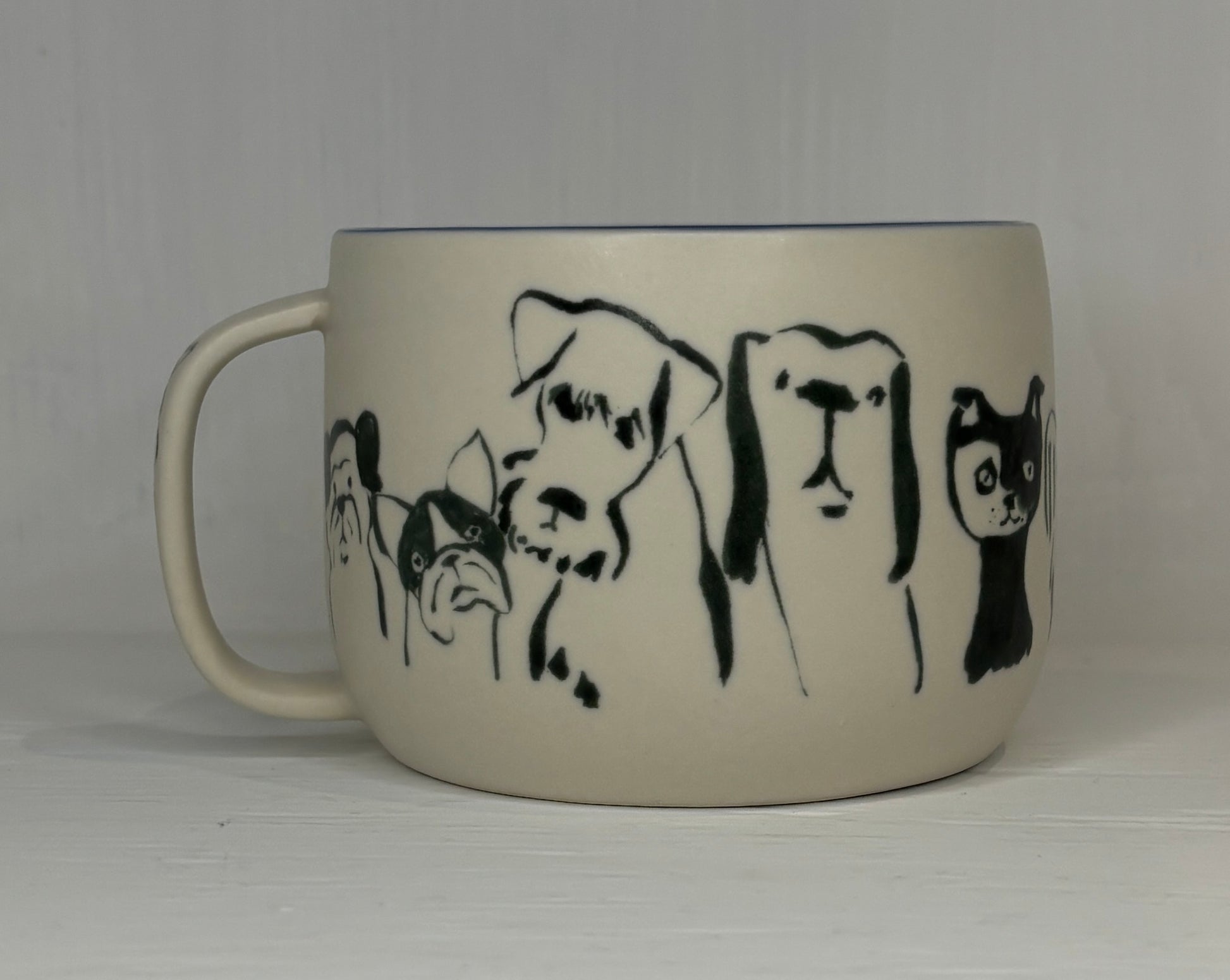 Mug with black line drawings of dogs and a cat on a plain background