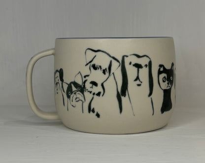 Mug with black line drawings of dogs and a cat on a plain background