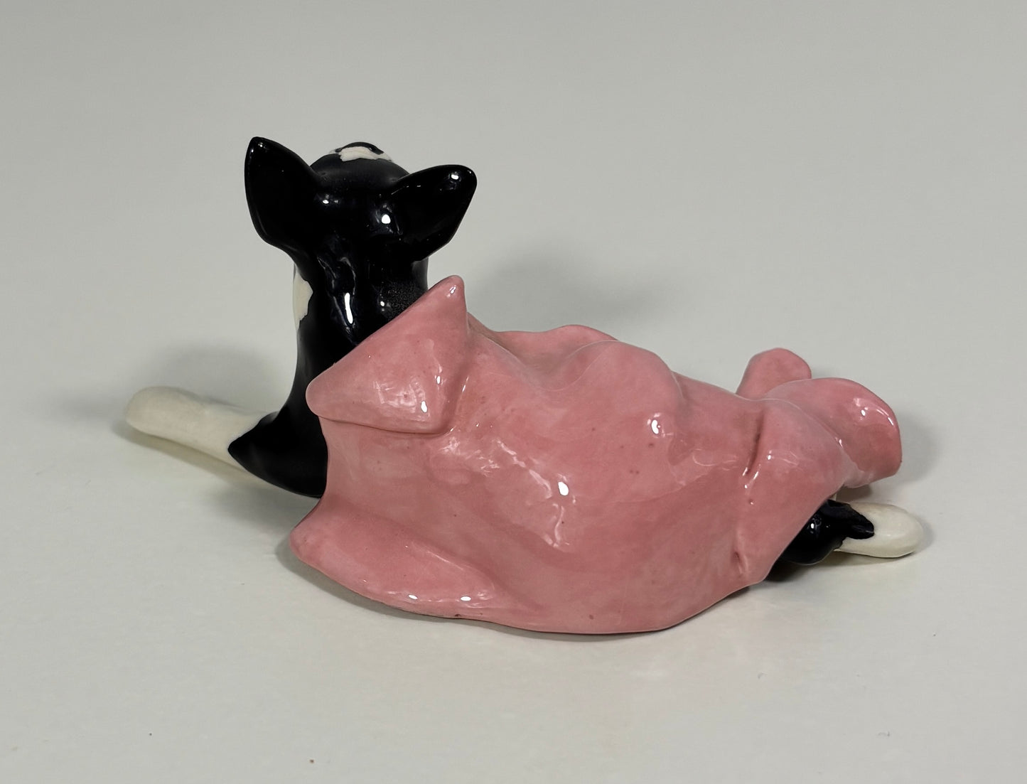 Pink and black ceramic cat-shaped object on a white background