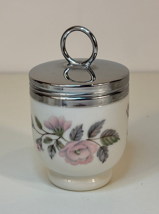 Small ceramic jar with floral design and silver lid on a white background