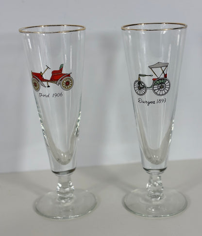 Two glass tumblers with vintage vehicle illustrations on a plain background