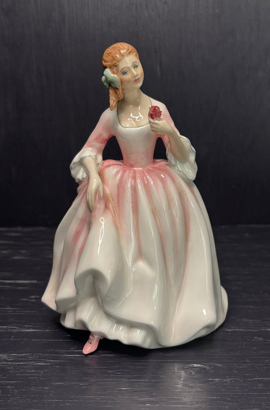 Porcelain figurine of a woman in a white dress with a red rose on a dark background