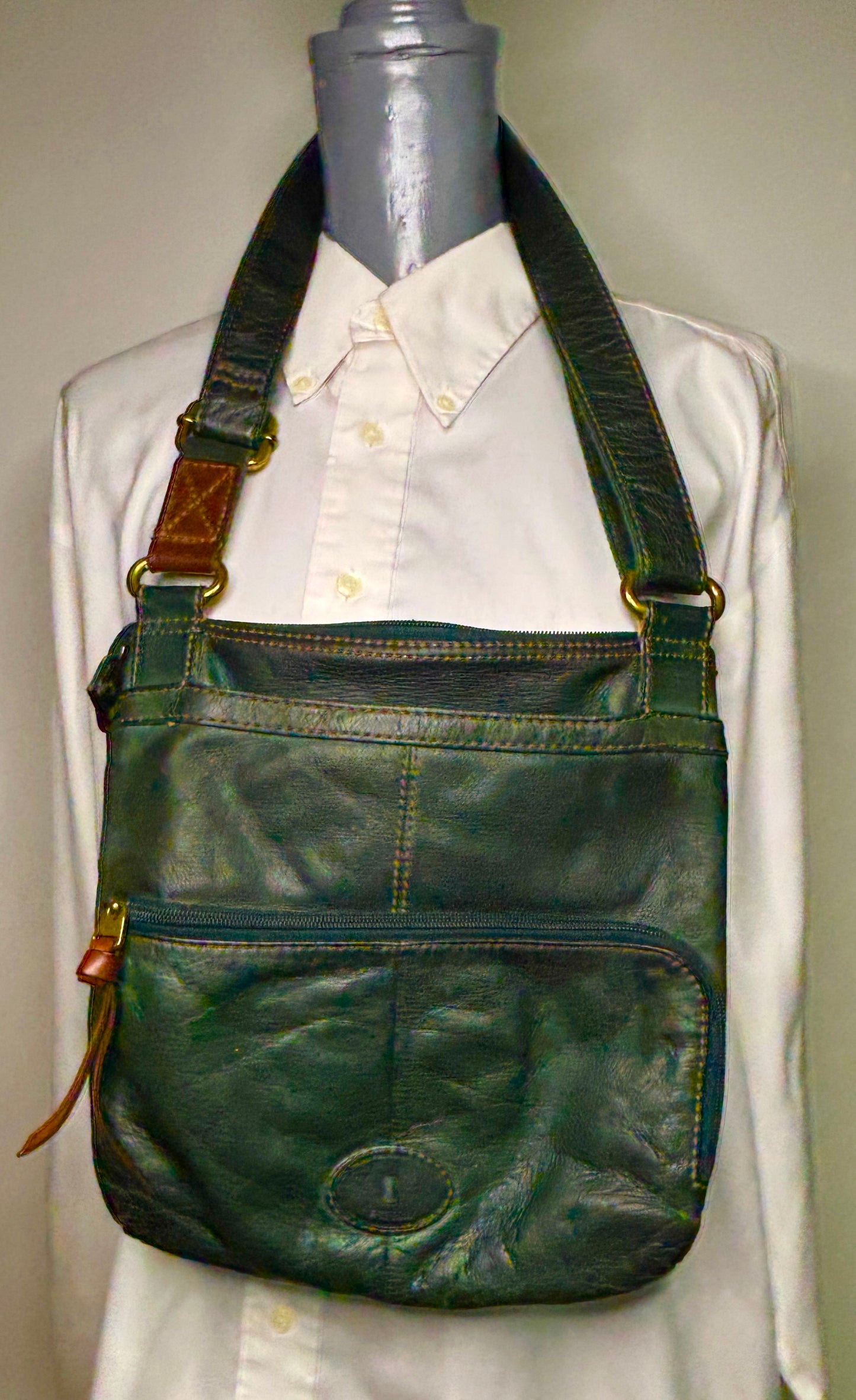 Green leather crossbody bag on a mannequin with a white shirt