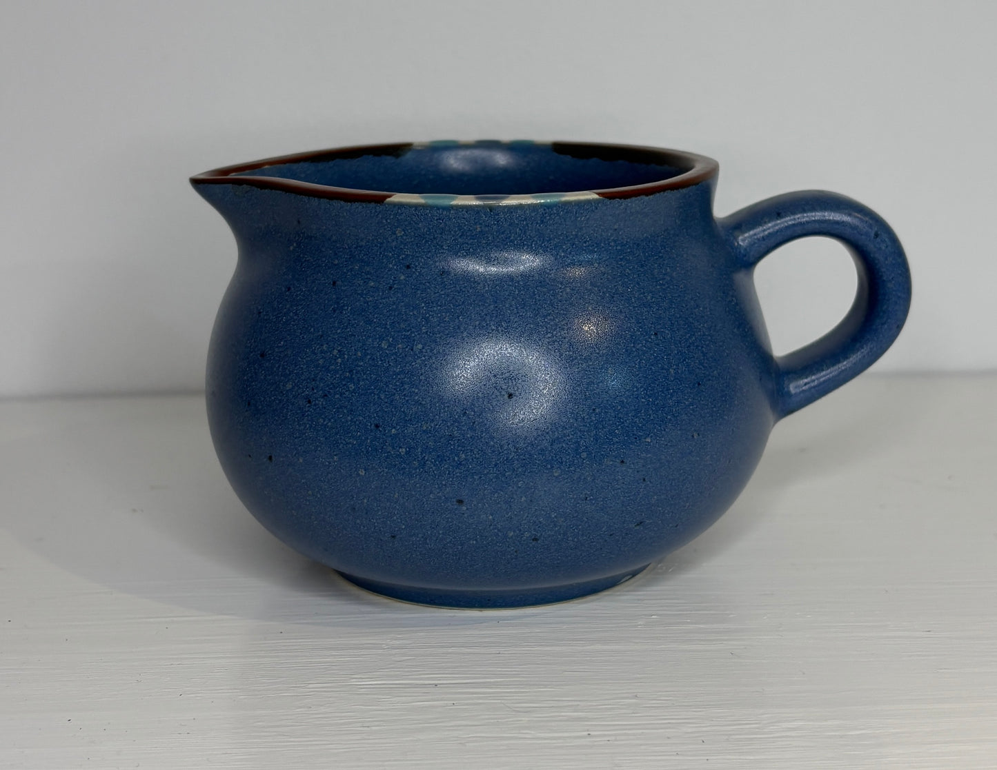 Blue ceramic creamer on a white background