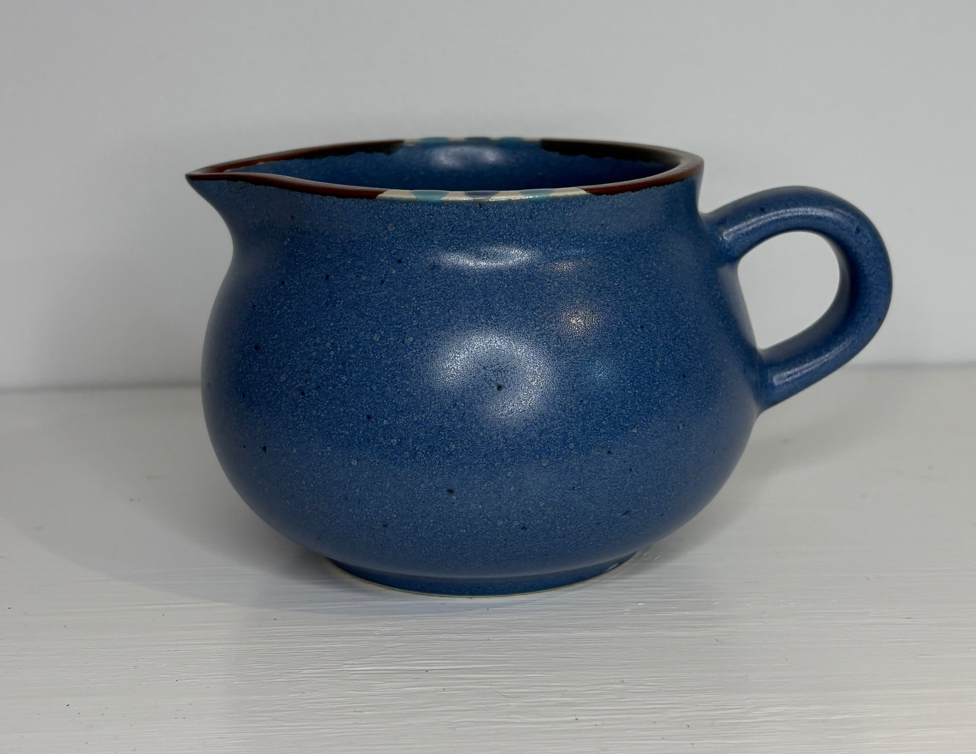 Blue ceramic creamer on a white background