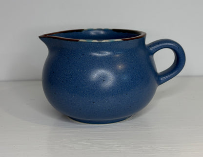 Blue ceramic creamer on a white background