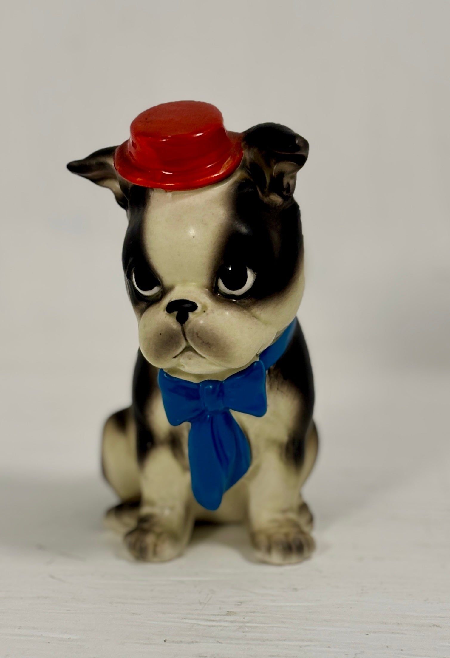 Dog figurine with a red hat and blue bow tie on a white background