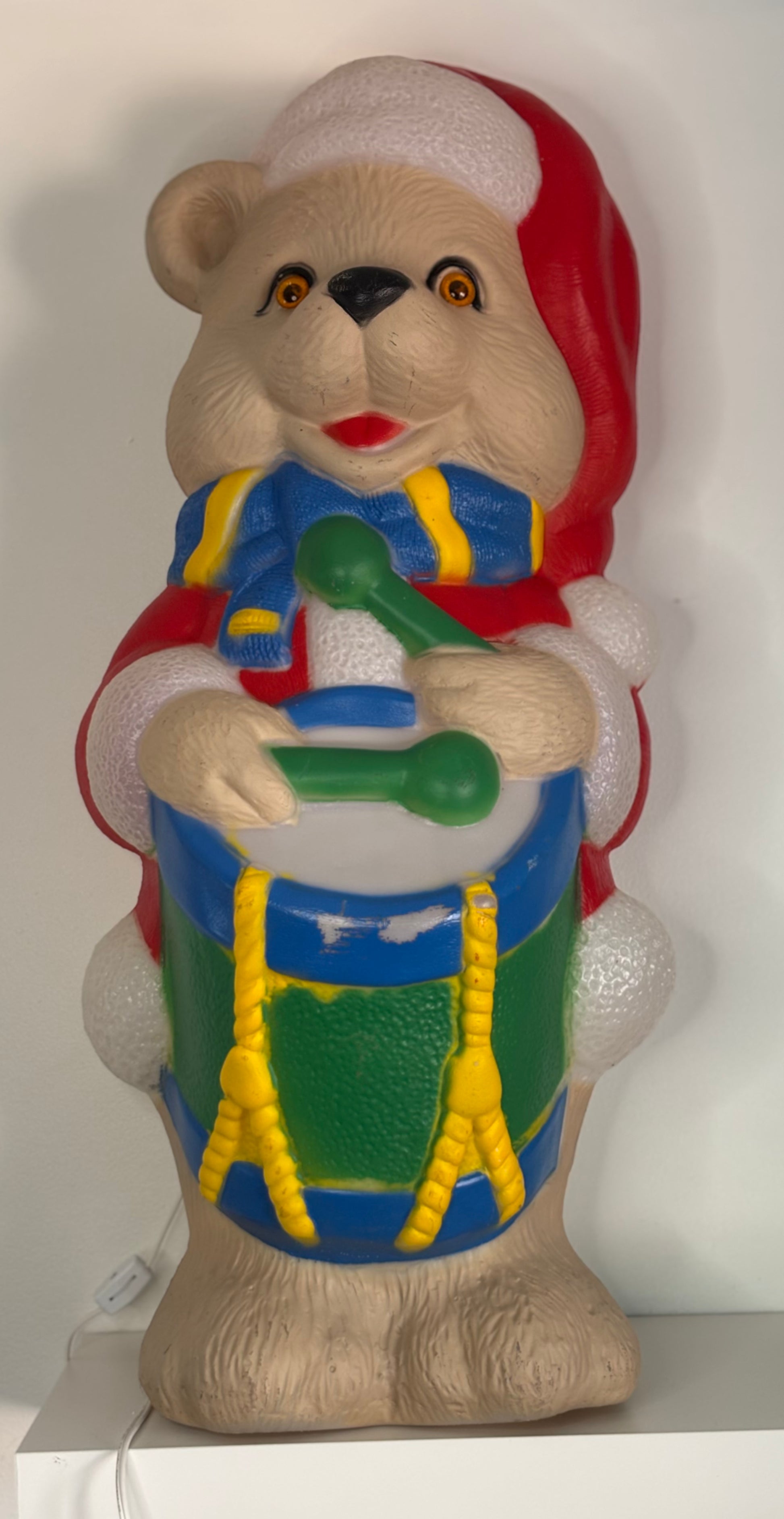 Colorful bear figurine playing a drum on a white background