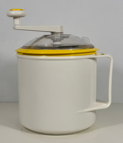 A vintage-style hand-crank ice cream maker with a white body, yellow accents, and a clear lid, shown against a plain light gray background.