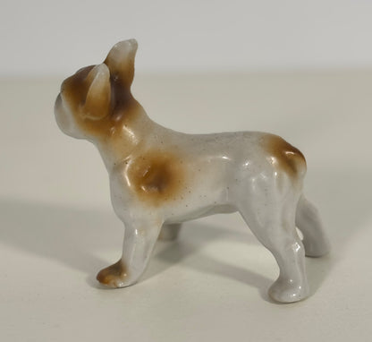 Small ceramic dog figurine with brown spots on a white background