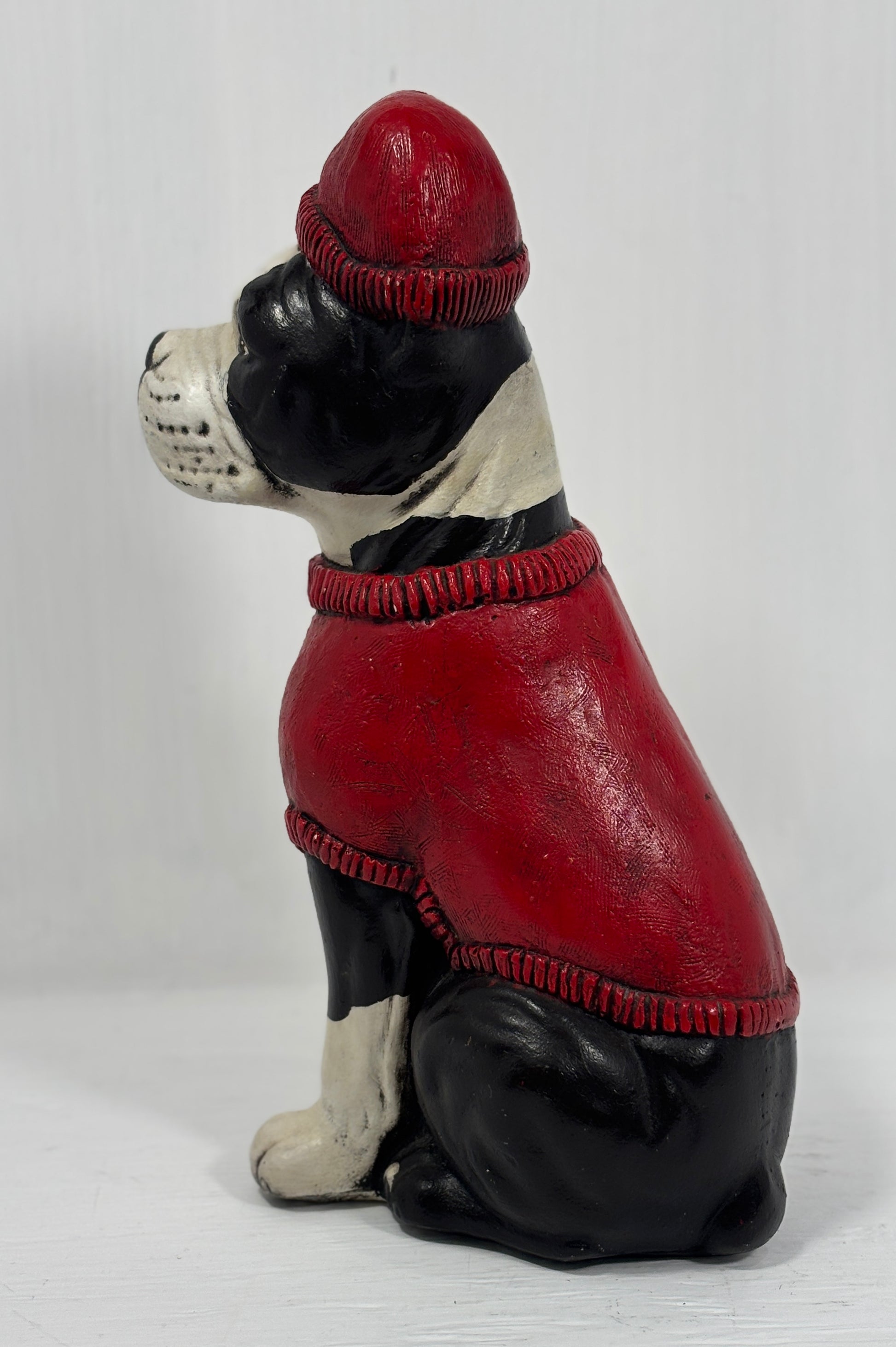 Dog figurine wearing a red sweater and hat on a white background