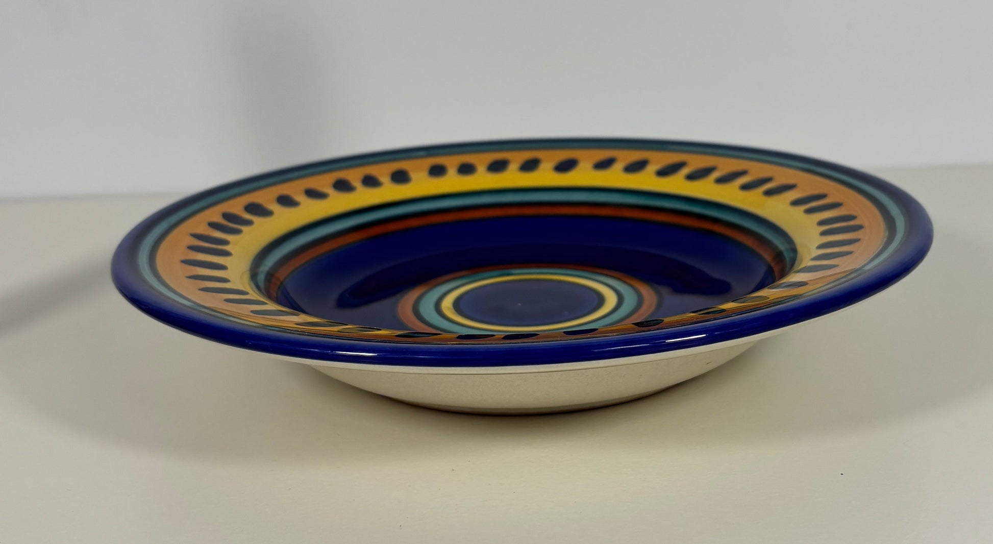 Ceramic bowl with blue and yellow decorative rim on a white background