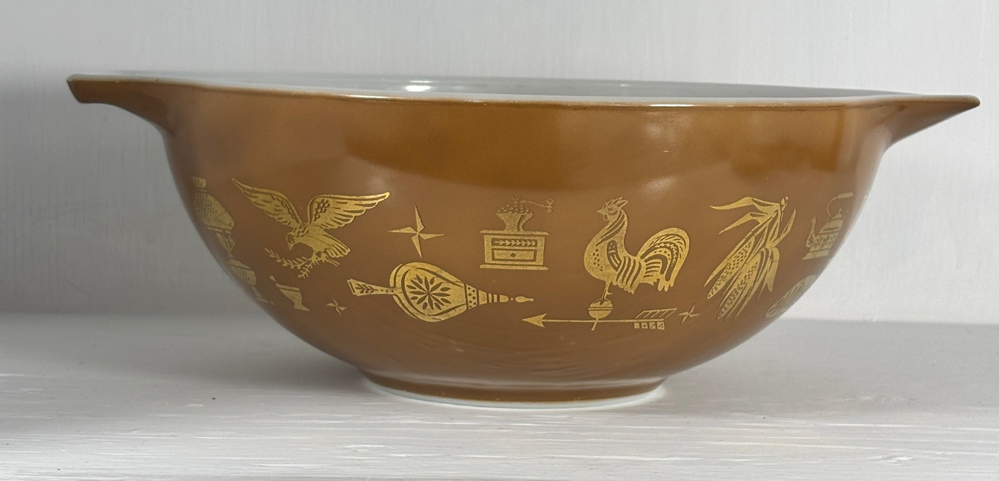 Brown bowl with gold embossed designs on a white background