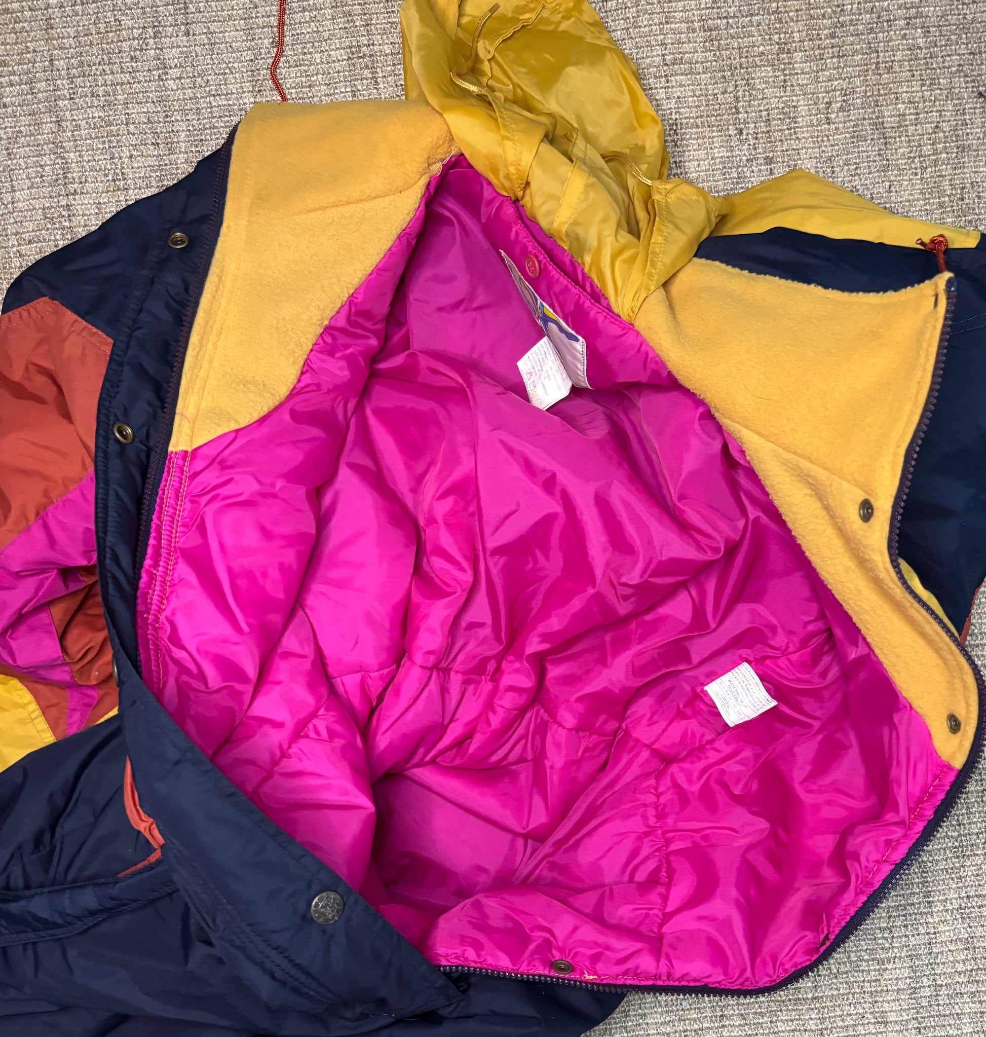 Multicolored puffer jacket with pink interior on a textured surface