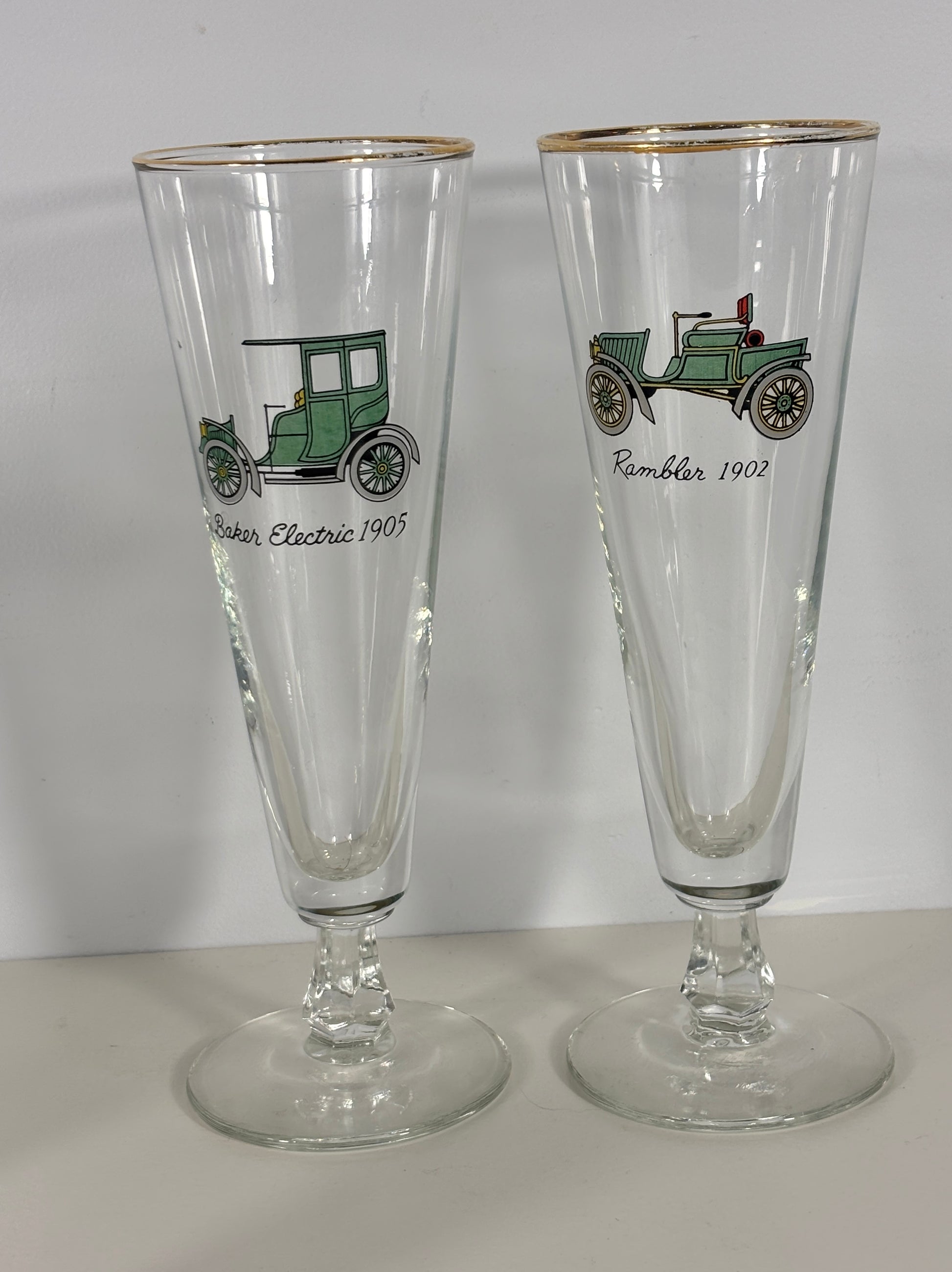 Two tall clear glasses with vintage car illustrations on a white background