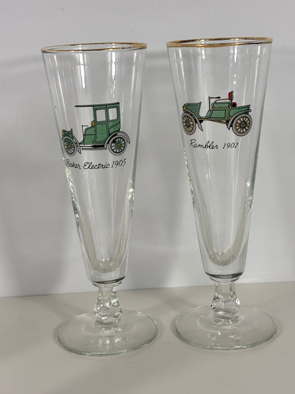 Two tall clear glasses with vintage car illustrations on a white background