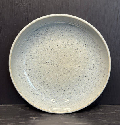 Speckled ceramic plate on a dark background