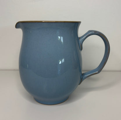 Blue ceramic pitcher on a plain background