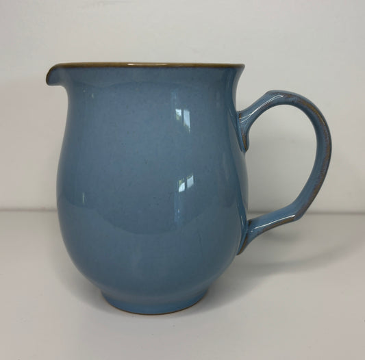 Blue ceramic pitcher on a plain background