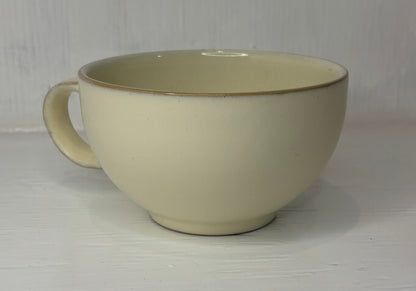 Beige ceramic mug with a brown rim on a white background