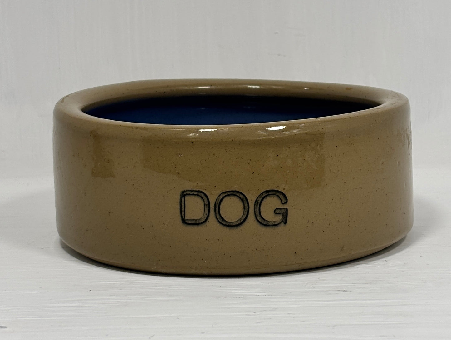 Beige ceramic dog bowl with 'DOG' engraving on a white background