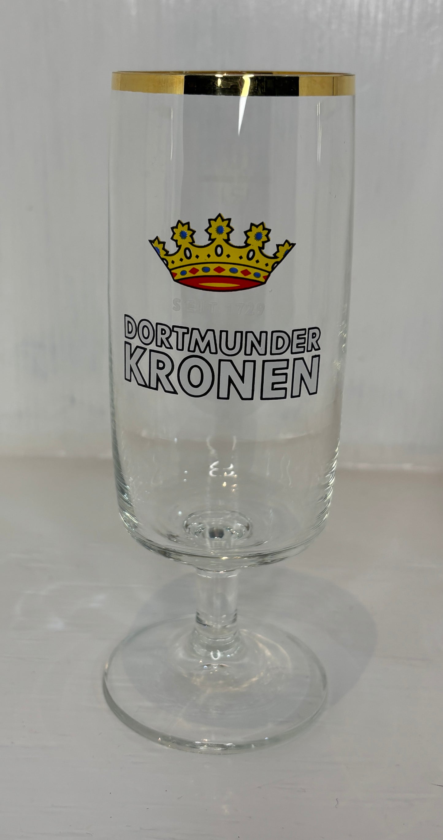Glass with 'Dortmunder Kronen' branding and a crown emblem on a white background