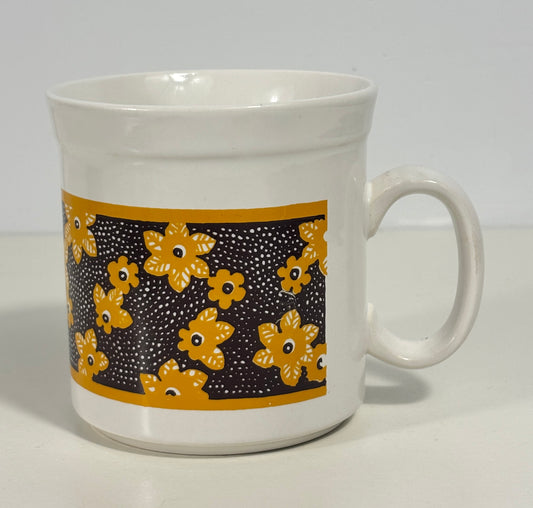 White mug with yellow floral pattern on a white background