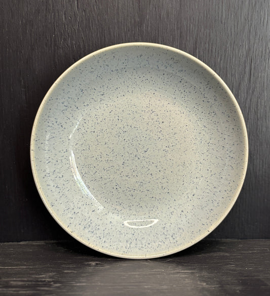 Speckled ceramic plate on a dark wooden surface