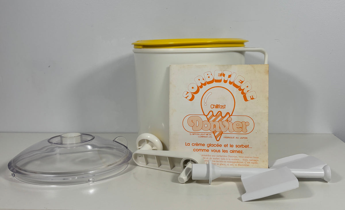 Vintage French sorbet maker set with a white plastic container, yellow lid, clear plastic bowl, white plastic tools, and an instruction booklet.