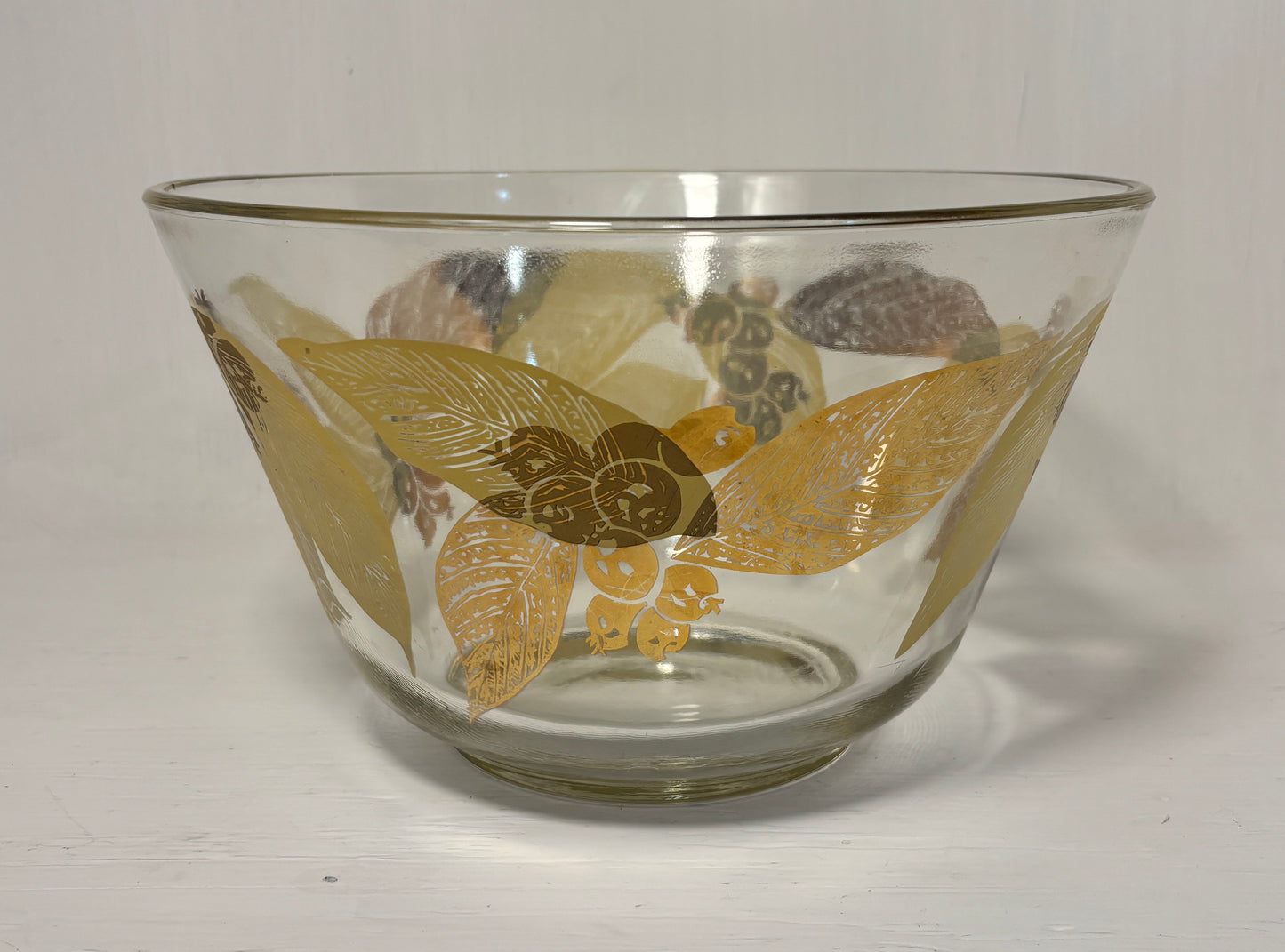 Clear glass bowl with gold floral patterns on a white background